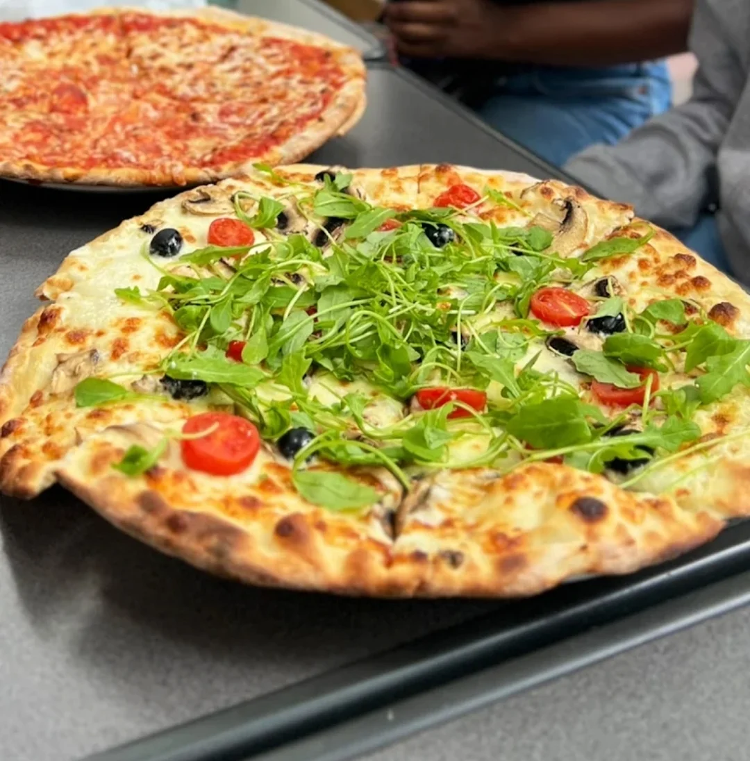 Pizza à la roquette, tomates cerises et olives, servie chez Vite et Bien