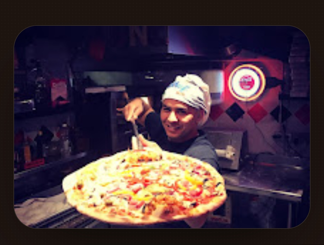 Notre pizzaiolo présentant une pizza fraîche sortie du four à Vite et Bien