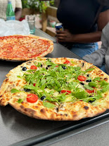 Pizza à la roquette, tomates cerises et olives, servie chez Vite et Bien